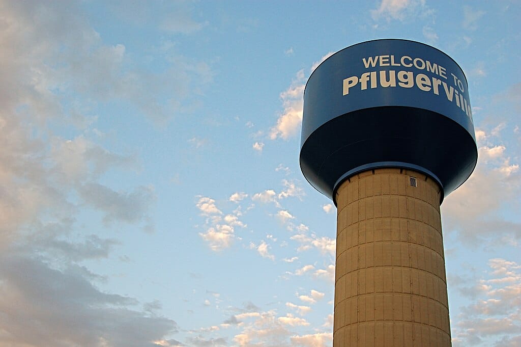 Pflugerville water tower against a cloudy sky.