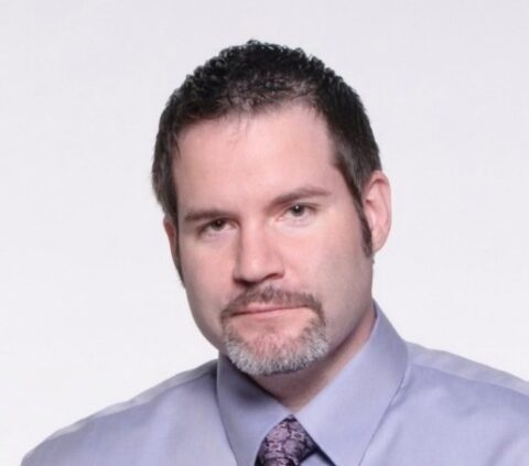 Professional headshot of man in lavender shirt and tie