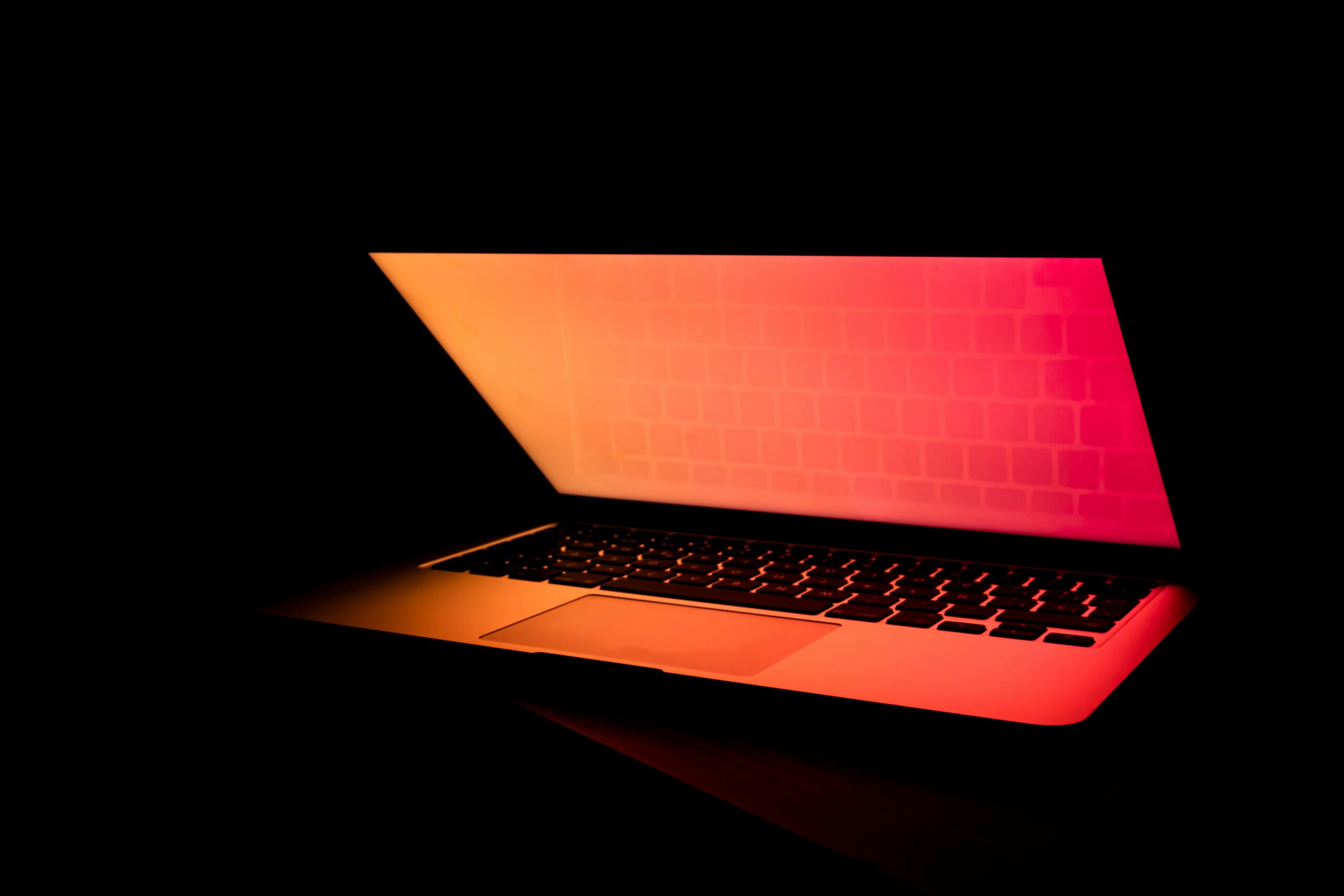 Laptop glowing with red light in dark room